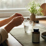 Hands measuring magnesium powder into glass