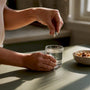 Hands taking magnesium and vitamin D capsules with water