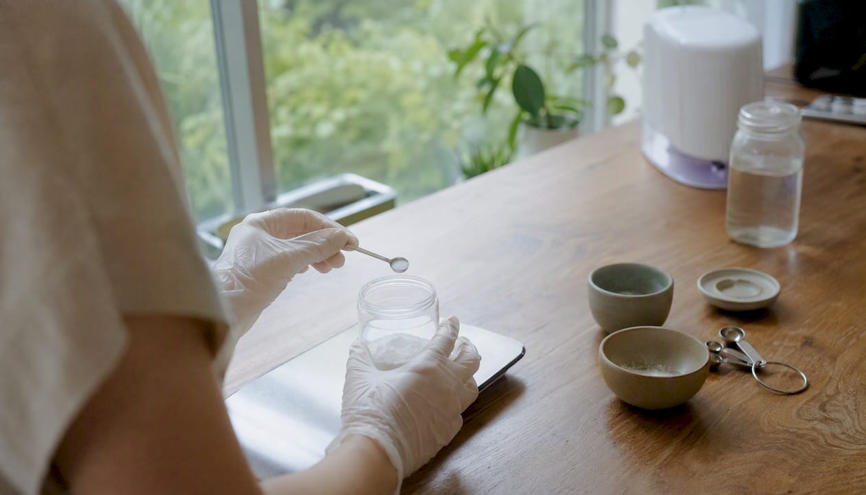 Gloved hand measuring powder sample in lab
