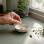 Hand pouring vegan supplement capsules into bowl