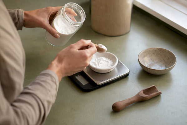 Hands measuring magnesium glycinate powder on scale