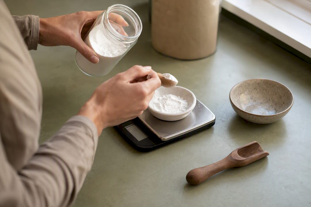 Hands measuring magnesium glycinate powder on scale