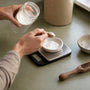 Hands measuring magnesium glycinate powder on scale