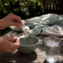 Hands scooping magnesium powder into a spoon
